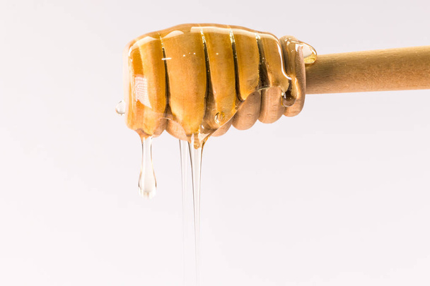 Miel goteando de un tarro de miel de madera aislado en blanco
 - Foto, imagen