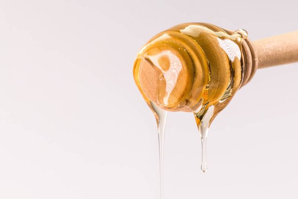 白で隔離される木製蜂蜜ディッパーから滴る蜂蜜 - 写真・画像
