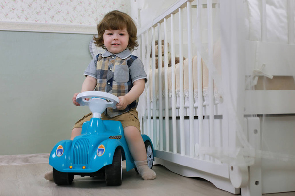 litle boy sentar em um carro de brinquedo
 - Foto, Imagem