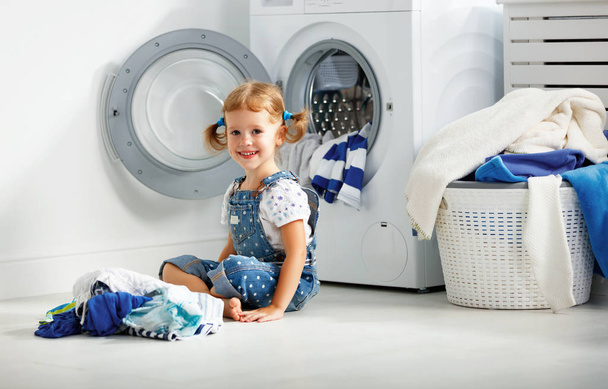 ребенок весело счастливая маленькая девочка стирать одежду в прачечной
 - Фото, изображение