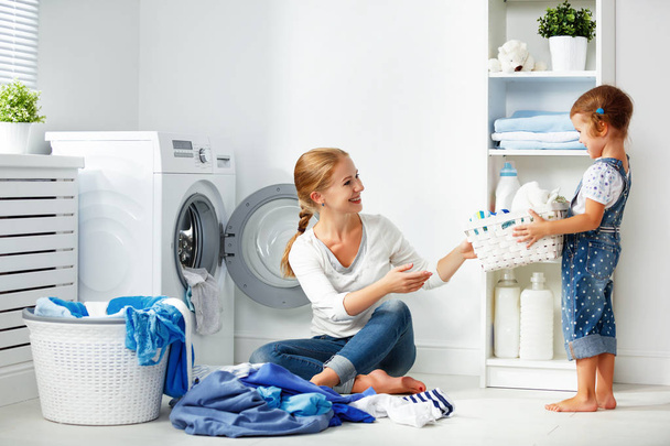 família mãe e criança menina pouco ajudante na lavanderia perto da máquina de lavar roupa e roupa suja
 - Foto, Imagem