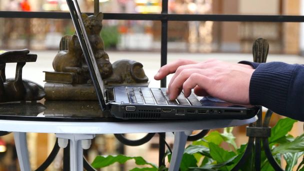 Männliche Hände tippen auf der Tastatur eines Laptops in einem Einkaufszentrum - Foto, Bild