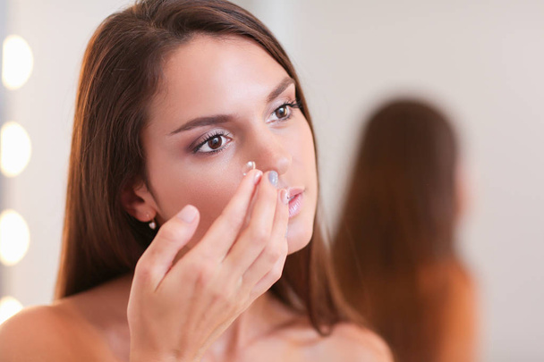 Attractive young woman applying cream on her Face - Φωτογραφία, εικόνα