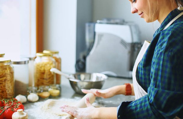 Beautiful woman cooking cake in kitchen standing near desk - Φωτογραφία, εικόνα