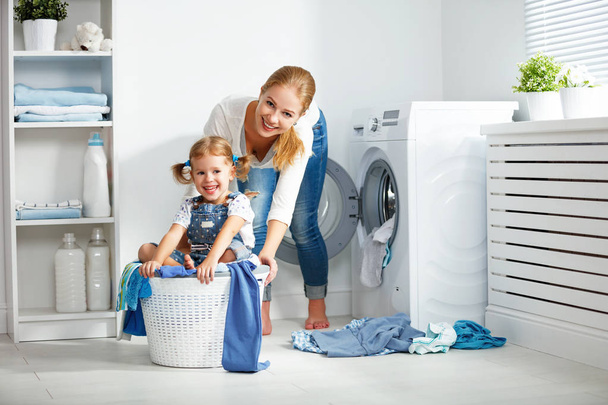 familia madre e hijo niña en la sala de lavandería cerca de lavar machi
 - Foto, Imagen
