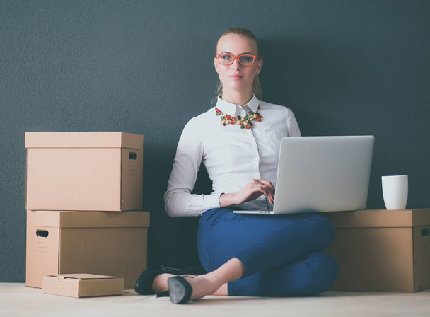 Woman sitting on the floor near a boxes with laptop - Photo, Image