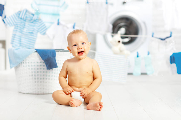 divertido bebé feliz niño para lavar la ropa y se ríe en la lavandería
 - Foto, Imagen