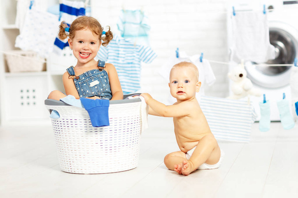Pomocnicy funny kids szczęśliwy siostra i brat w pralni, do prania odzieży, odtwarzanie i śmiechu - Zdjęcie, obraz
