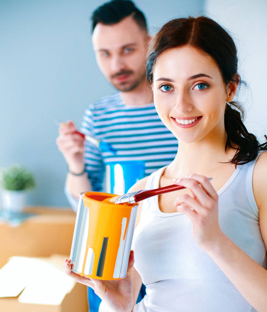 Portrait happy smiling young couple painting interior wall of new house - Foto, Imagem
