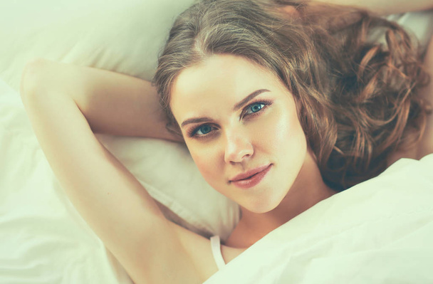 Pretty woman lying down on her bed at home - Fotografie, Obrázek