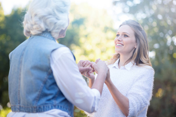 woman holding hands with grandmother in park - Photo, Image