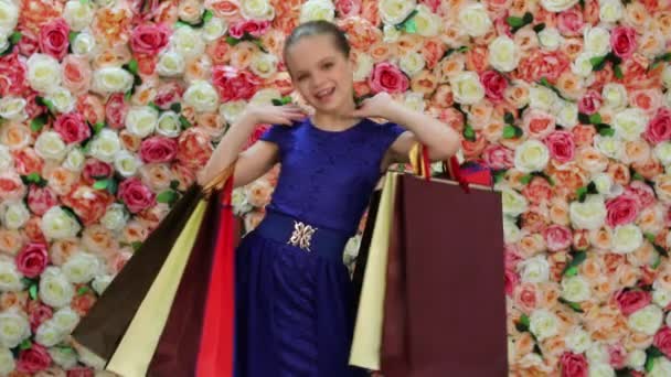 Childrens shopping. Portrait of blonde little girl, background of bright floral wall - Imágenes, Vídeo