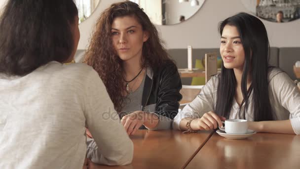 Две девушки внимательно слушают своего друга в кафе
 - Кадры, видео