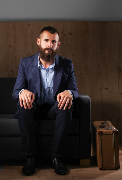 Businessman sitting the sofa in office lobby, isolated on dark background - Zdjęcie, obraz