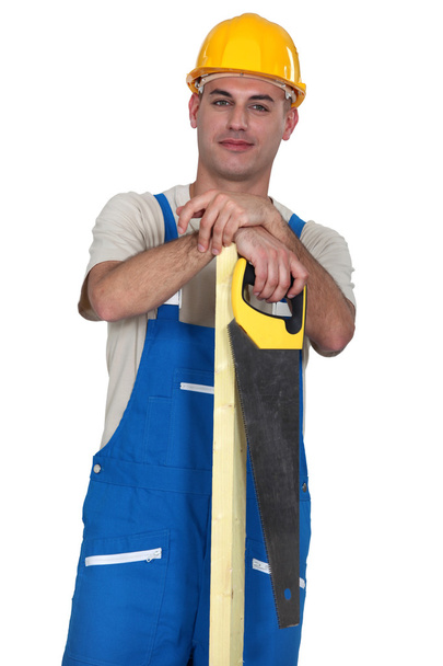 Craftsman holding a board and a handsaw - Фото, изображение