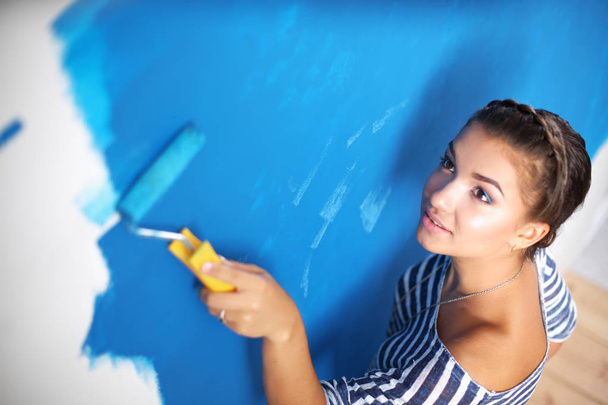 Beautiful young woman doing wall painting , standing - Photo, Image