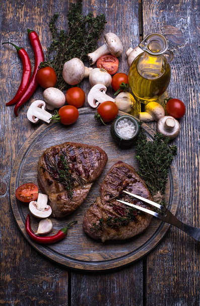  Beef Steak, salt, pepper, garlic, rosemary  on the black wooden board, background. - Фото, изображение