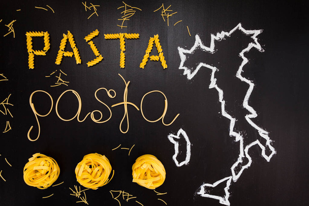 Words pasta made of cooked spaghetti and dry pasta on the black background with frame of country Italy written by chalk - 写真・画像