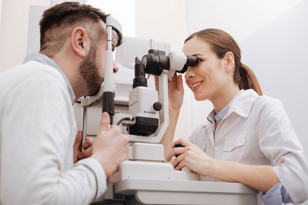 Joyful professional ophthalmologist scanning the eye of her patient - Foto, imagen