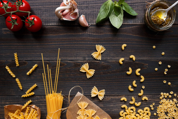 Dried mixed pasta and vegetables on the dark wooden table top view - 写真・画像