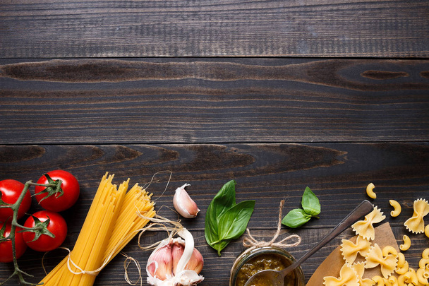 Dried mixed pasta and vegetables on the dark wooden table top view, with copy space - 写真・画像