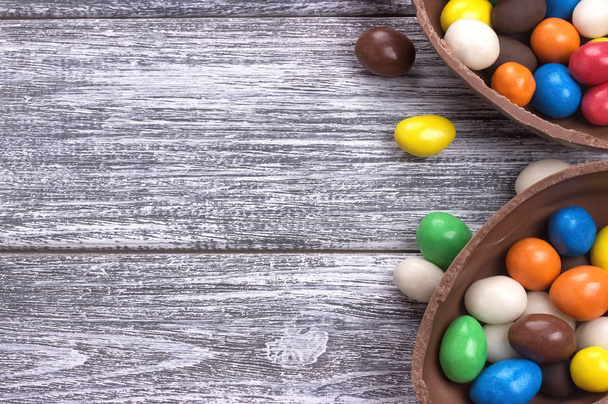 Easter chocolate egg with colorful explosion of candies and sweets on gray colored wooden background. - Fotografie, Obrázek