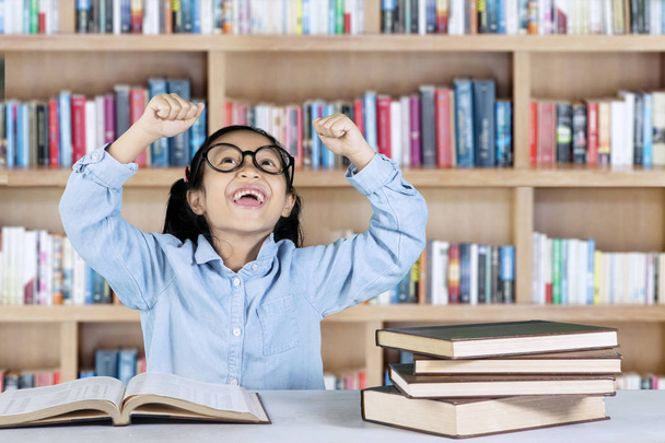 Elementary student celebrating her success in library  - Фото, изображение