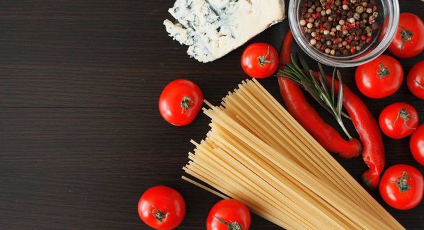 Esparguete de macarrão italiano e ingredientes de cozinha tomates cereja parmesão verdes. Comida italiana. Vista superior com espaço de cópia
 - Foto, Imagem
