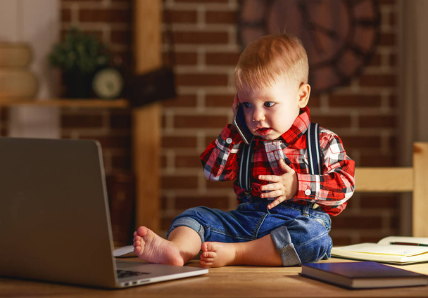 käsite vauva poika työskentelee tietokoneella ja puhuu puhelimessa
 - Valokuva, kuva