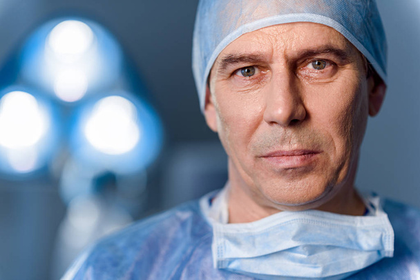 Serious doctor standing in operating room - 写真・画像