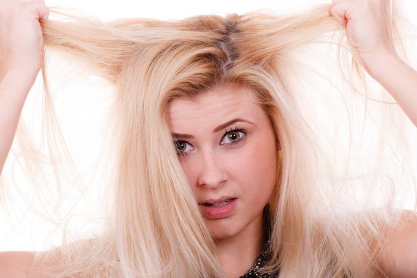 Blonde woman holding her dry hair - Foto, imagen