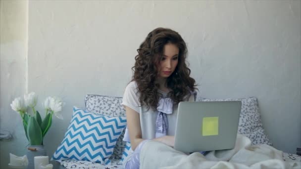 An adult girl who recently woke up checks the mail on the laptop. - Video