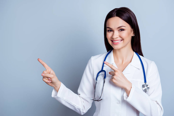 Friendly smiling young female doctor pointing with finger to the - Photo, image