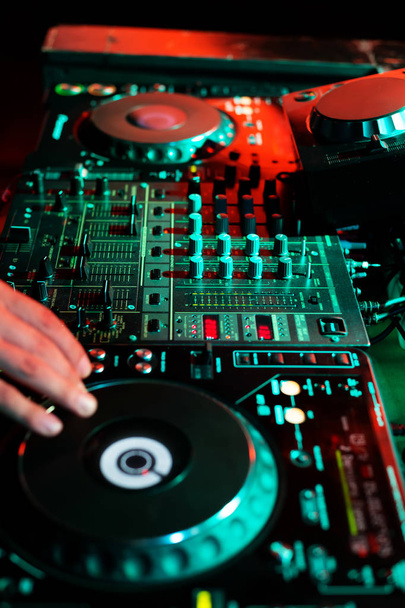 DJ playing music in night club party. Turntable equipment in dar - Photo, Image