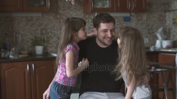 Kaksi pientä tytärtä juoksee isänsä luo ja antaa hänelle halauksia ja suukkoja. Yksinhuoltajaisä lastensa kanssa. hidastettuna
 - Materiaali, video
