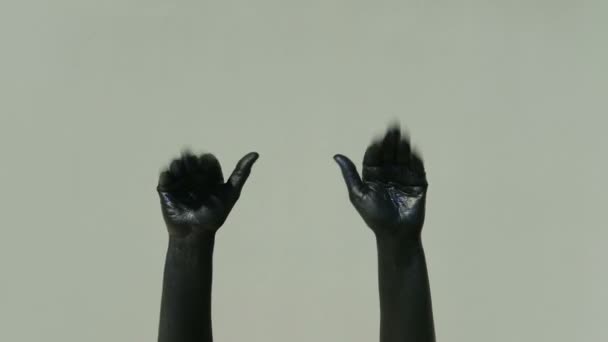 Actor mime with black hands shows gesture goodbye on a gray background - Footage, Video