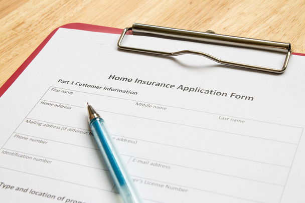 Formulário de pedido de seguro de casa com arquivo vermelho na mesa de madeira
 - Foto, Imagem