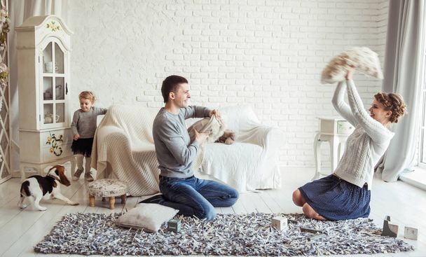 happy family and pet dog playing with pillows in spacious living room - Zdjęcie, obraz