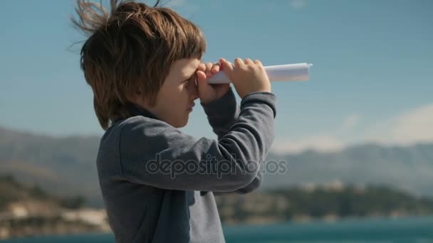 boy fold piece of paper looking into the distance trumpet to mountains - Footage, Video