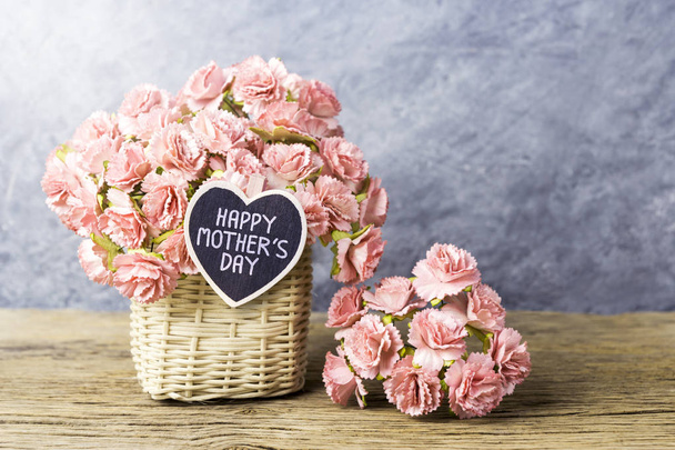 Happy mothers day concept of paper carnation in weave basket on old wood with copy space  - Photo, image