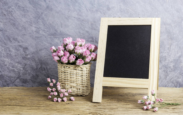Papier rosa Rosenblüten und leere schwarze Tafel auf altem Holz - Foto, Bild