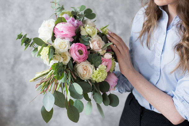Florist at work: pretty young woman making fashion modern bouquet of different flowers - Foto, Bild
