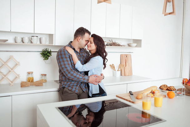 Ευτυχισμένο ζευγάρι αγκαλιάζει στην κουζίνα ΣΤΕΙΛΕ λευκή loft - Φωτογραφία, εικόνα