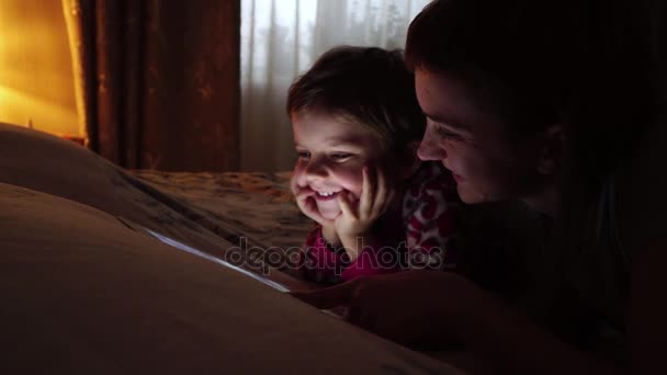 Крупный план матери и ее маленькой дочери, смотрящей планшет дома
. - Кадры, видео