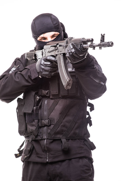 Armed terrorist in black mask and black uniform aiming with a gun. Portrait of good or bad guy - Photo, Image