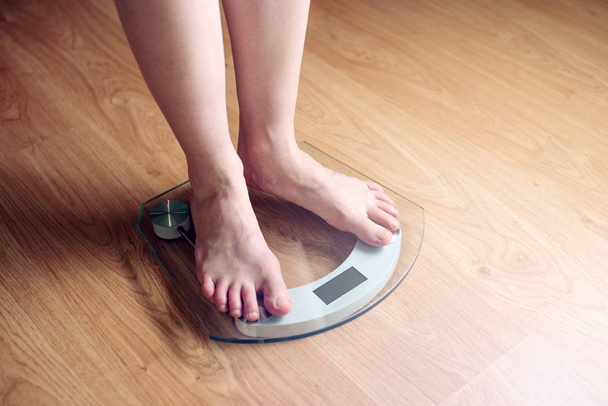 Pés femininos em pé em balanças eletrônicas para controle de peso
 - Foto, Imagem