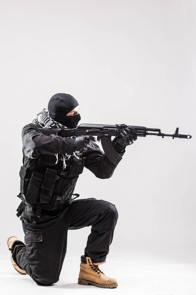Terrorist holding a machine gun in his hands aim isolated over white - Photo, Image