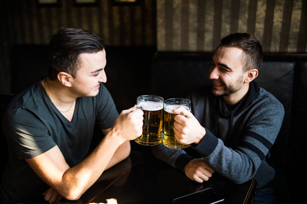 Kaksi nuorta miestä pubissa syömässä ja juomassa olutta pubissa.
 - Valokuva, kuva