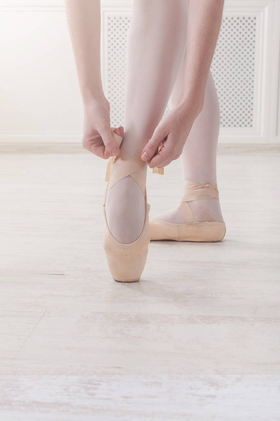 Closeup legs of ballerina puts on pointe ballet shoes - Fotó, kép