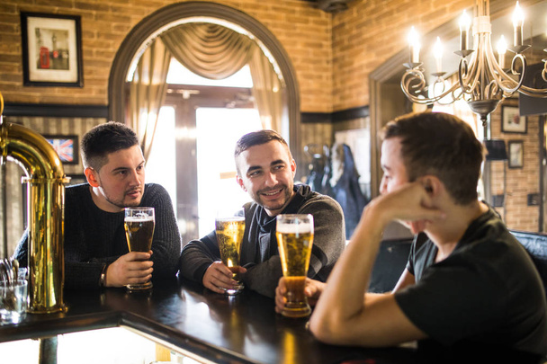 De vieux amis joyeux s'amusent et boivent de la bière pression au comptoir du bar dans le pub. Les amis se rencontrent
 - Photo, image